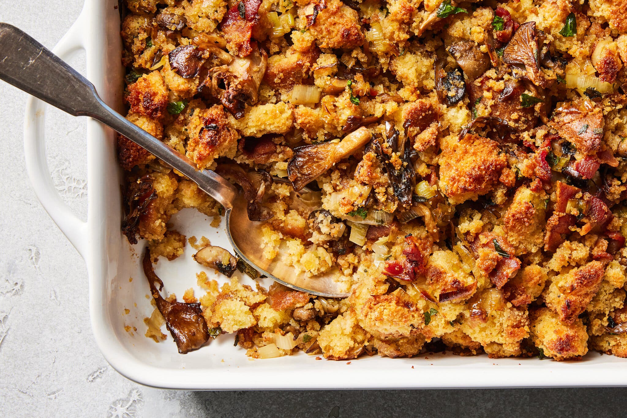 An overhead image of a rich mushroom stuffing in a baking dish. A single serving is removed from one corner.