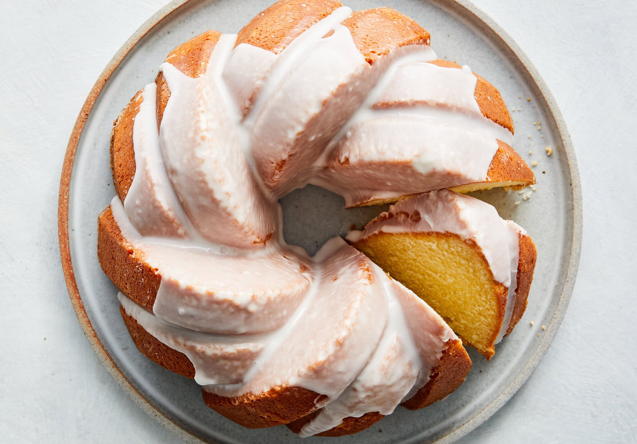 A pound cake coated in vanilla icing sits on a large plate.