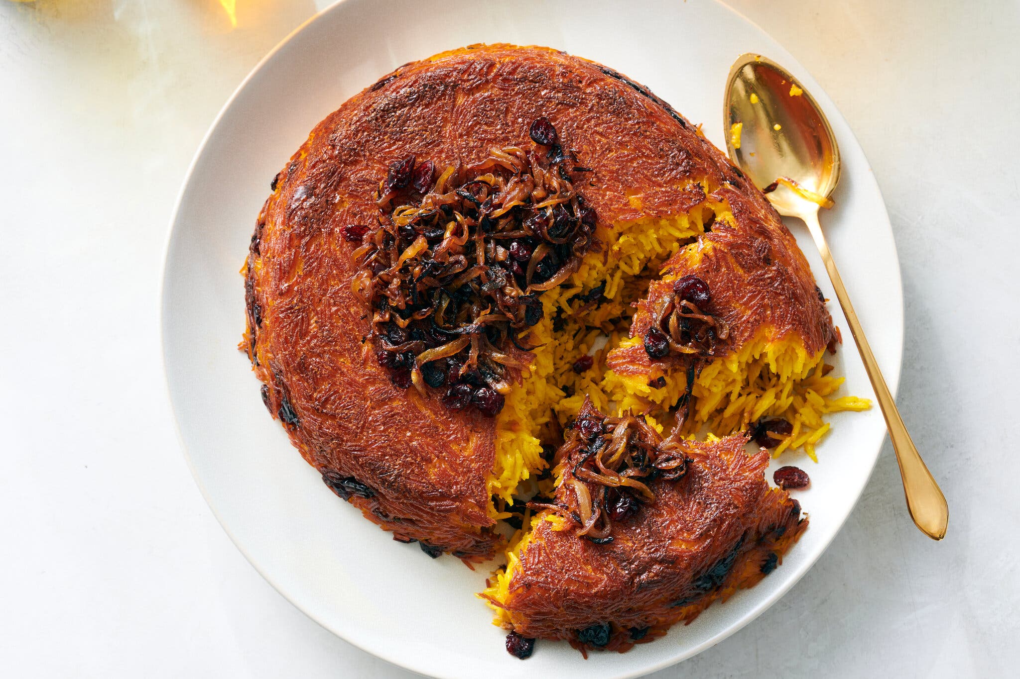 Tachin, the Iranian rice dish, sits on a plate with parts broken open.