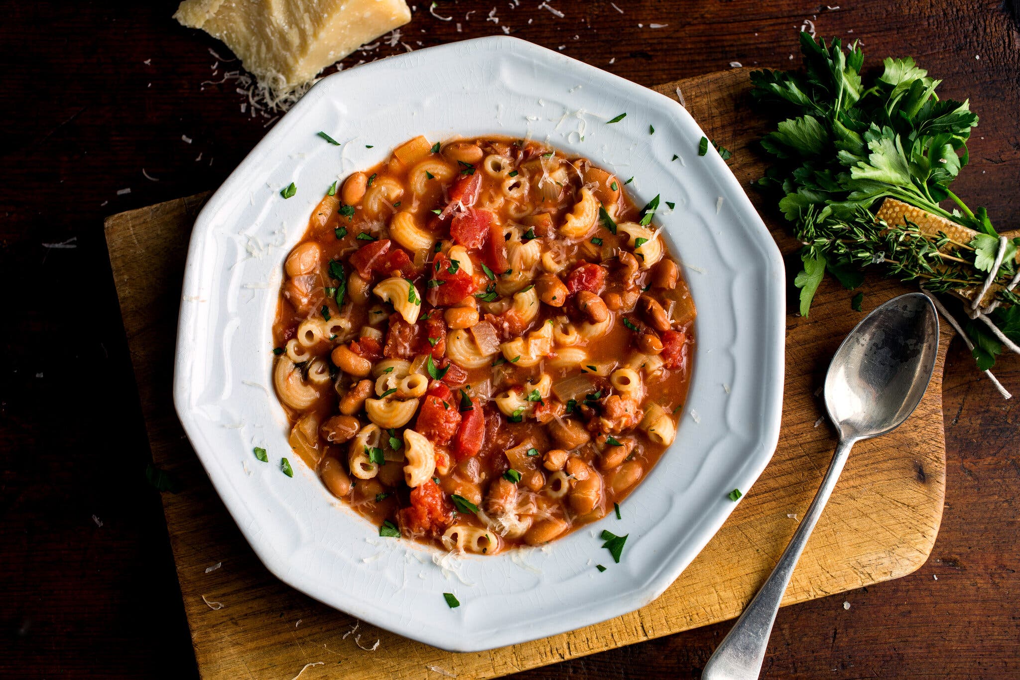 An overhead image of a wide-rimmed bowl holding pasta e fagioli, full of macaroni and beans.